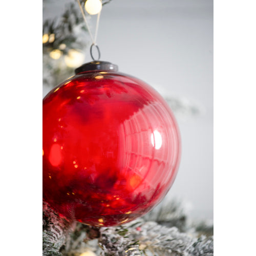 Red Christmas ornament hanging on a tree with a blurred background