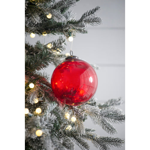 Red Christmas ornament on a decorated tree with lights