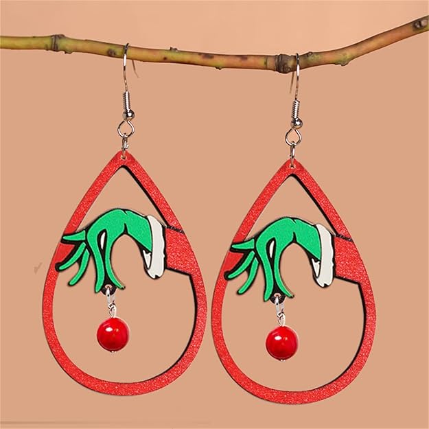 Teardrop-shaped earrings with green hands and red balls hanging from a branch on a beige background
