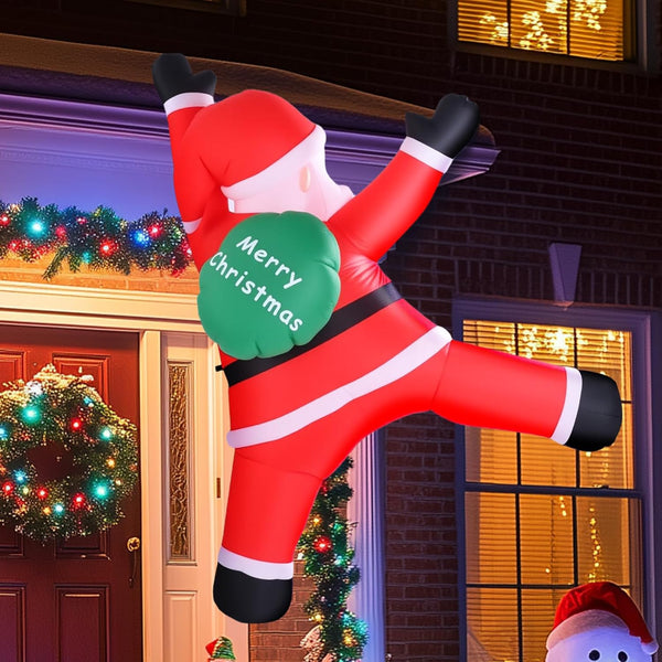 Inflatable Santa Claus decoration holding a 'Merry Christmas' sign in front of a decorated house.