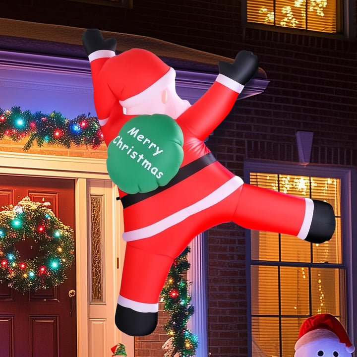Inflatable Santa Claus decoration holding a 'Merry Christmas' sign in front of a decorated house.