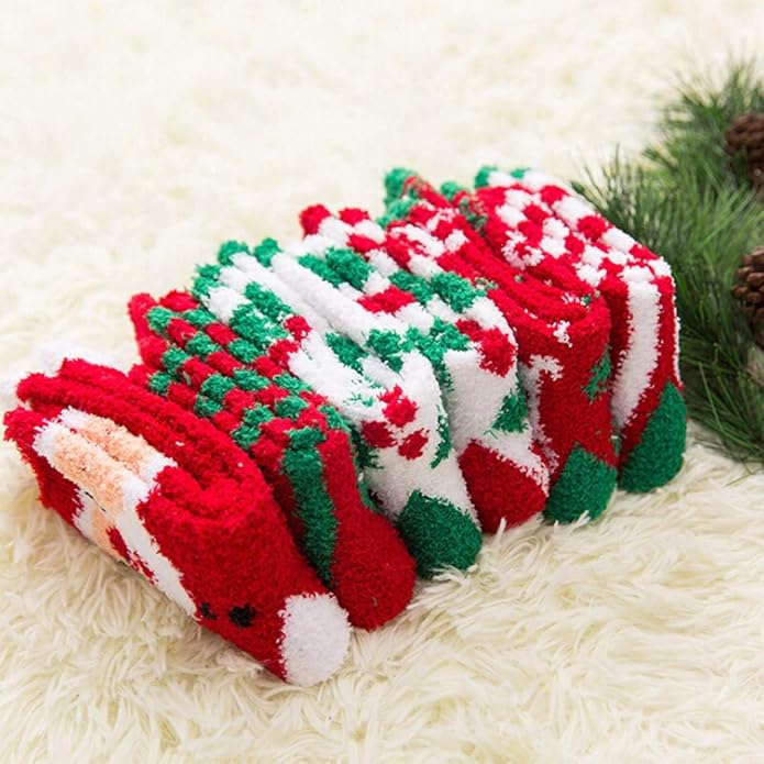 Set of red, green, and white Christmas-themed socks on a fluffy white surface with pine branches.