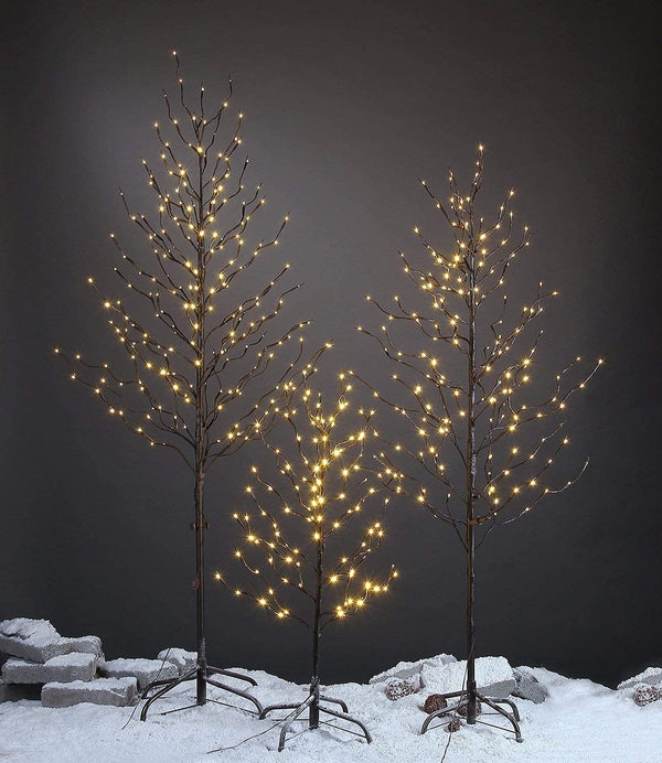 Decorative trees with lights on a snowy ground against a dark background