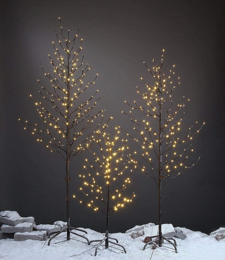 Decorative trees with lights on a snowy ground against a dark background
