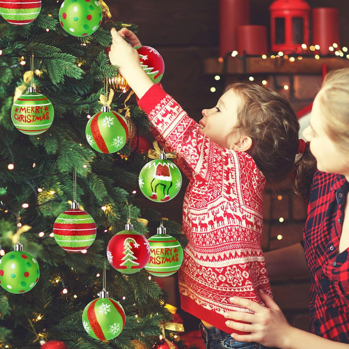 Child in a red and white sweater decorating a Christmas tree with ornaments.