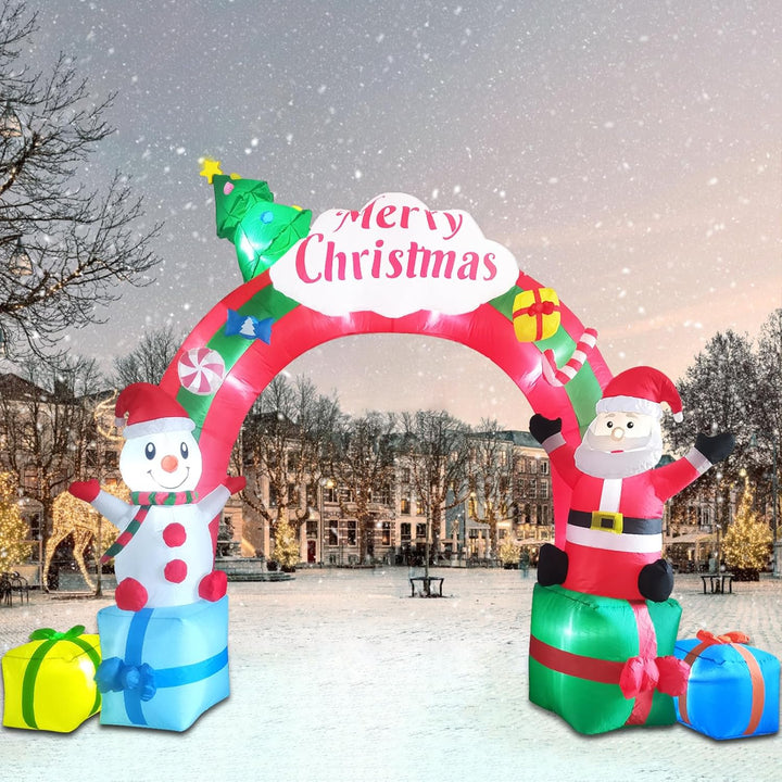 Inflatable Christmas arch with Santa Claus, snowman, and presents in a snowy outdoor setting.