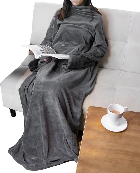 Person sitting on a couch wearing a gray lounge robe, reading a book with a cup of coffee nearby.