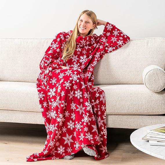 Person wearing a red snowflake-patterned blanket sitting on a couch.
