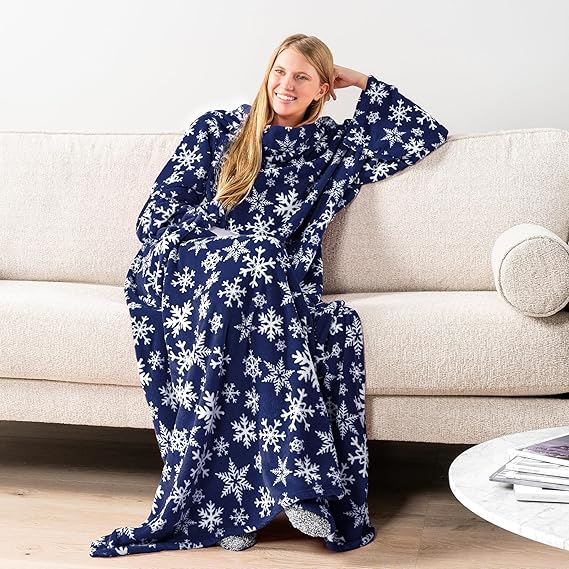Person wearing a navy blue blanket with white snowflake patterns, sitting on a couch.