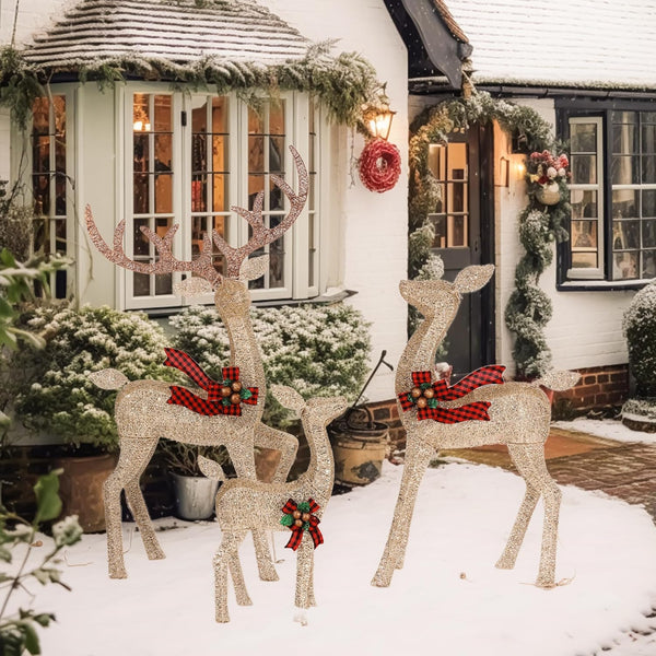 Decorative deer figures with red plaid bows in front of a house with Christmas decorations.