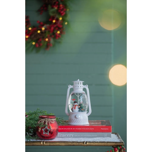 Decorative lantern with snowman figure on books against a festive background