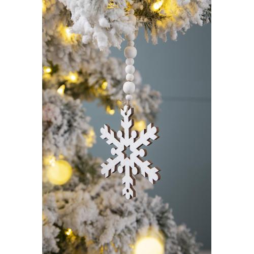 White snowflake ornament hanging on a decorated Christmas tree with lights.
