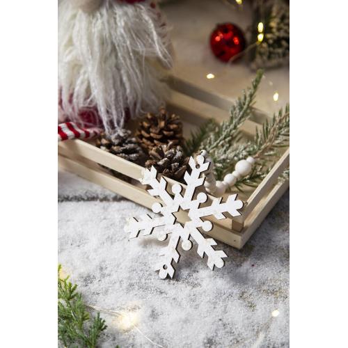 Wooden snowflake ornament on a decorative surface with Christmas decorations.