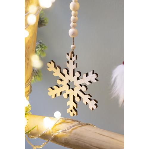 Wooden snowflake ornament hanging on a branch with lights